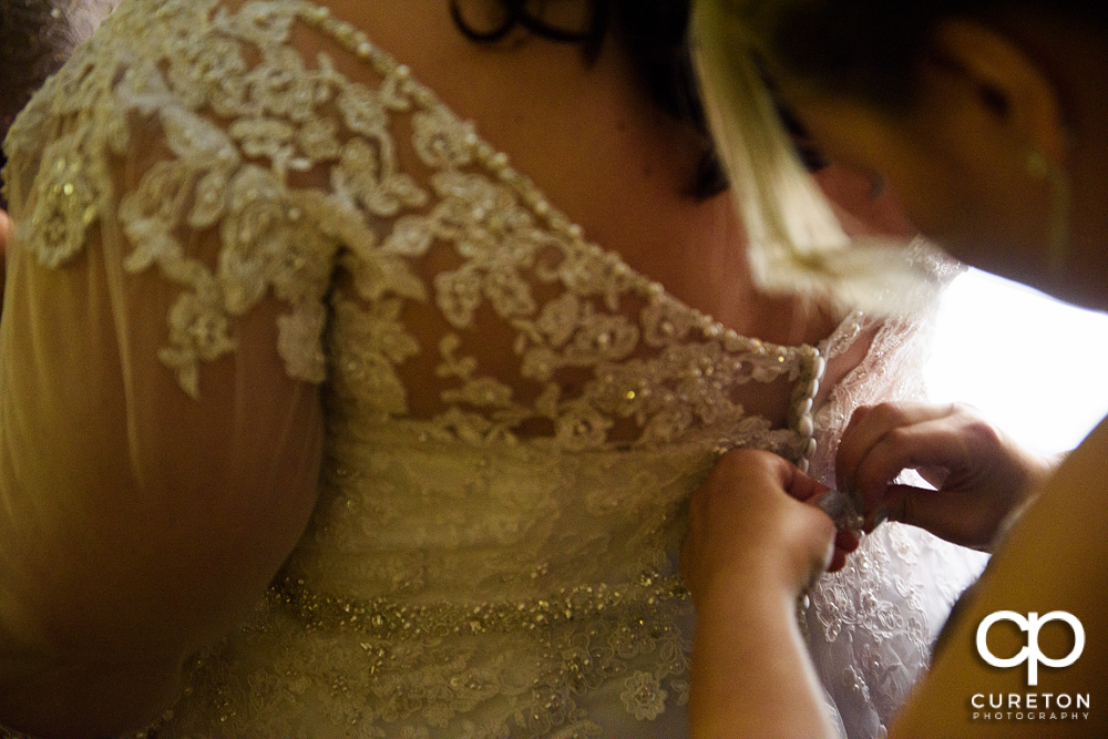 Bride getting the back of her dress buttoned.
