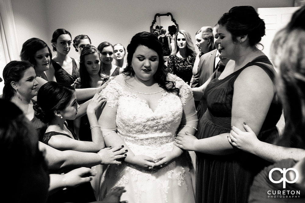 Bridal party praying with the bride before the ceremony.