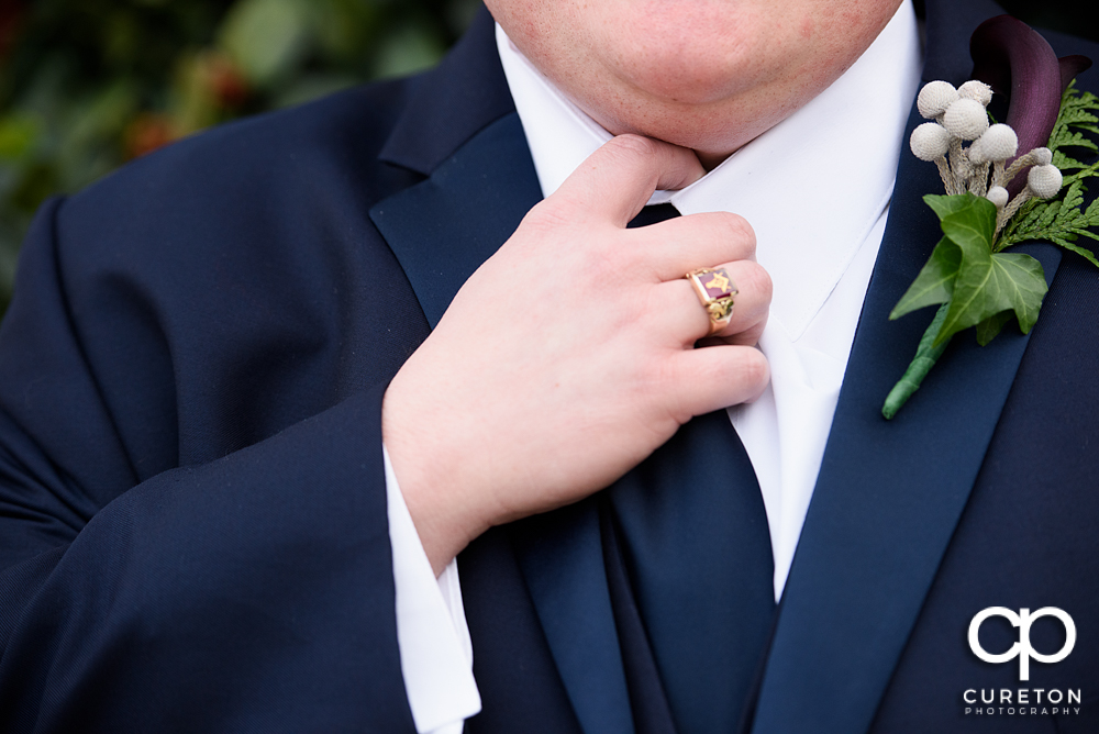 Groom straightening his tie.