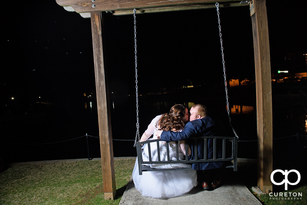 Bride and groom kissing on a park bench at Cleveland Park during the Spartanburg wedding reception.