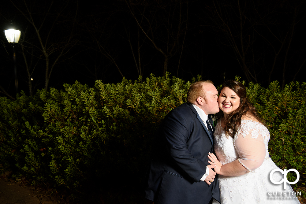 Groom kissing his bride on the cheek.