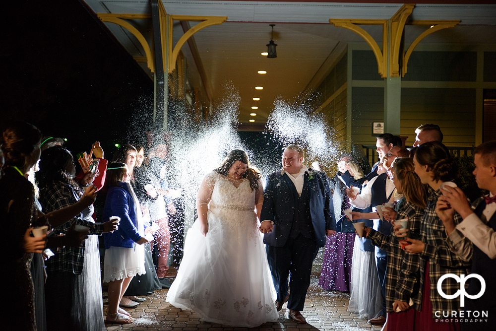 Bride and groom walking though a fake snow wedding leave.