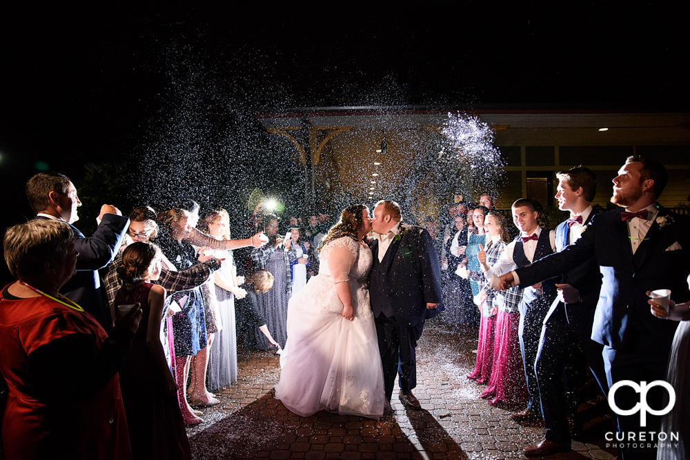 Bride and groom walking though a fake snow wedding leave.