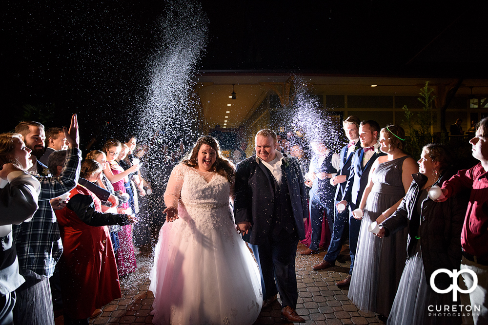 Bride and groom walking though a fake snow wedding leave.