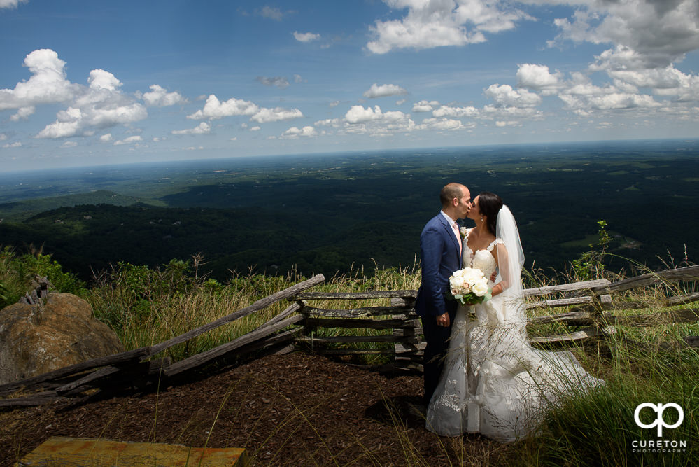 Newlyweds kissing on a cliff after their Glassy Chapel wedding.