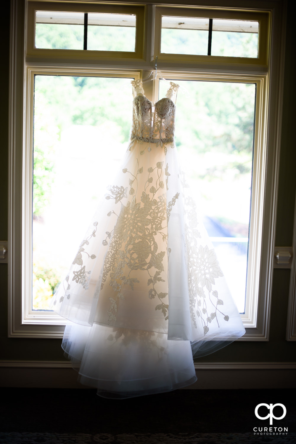 Bride's dress hanging in the window.