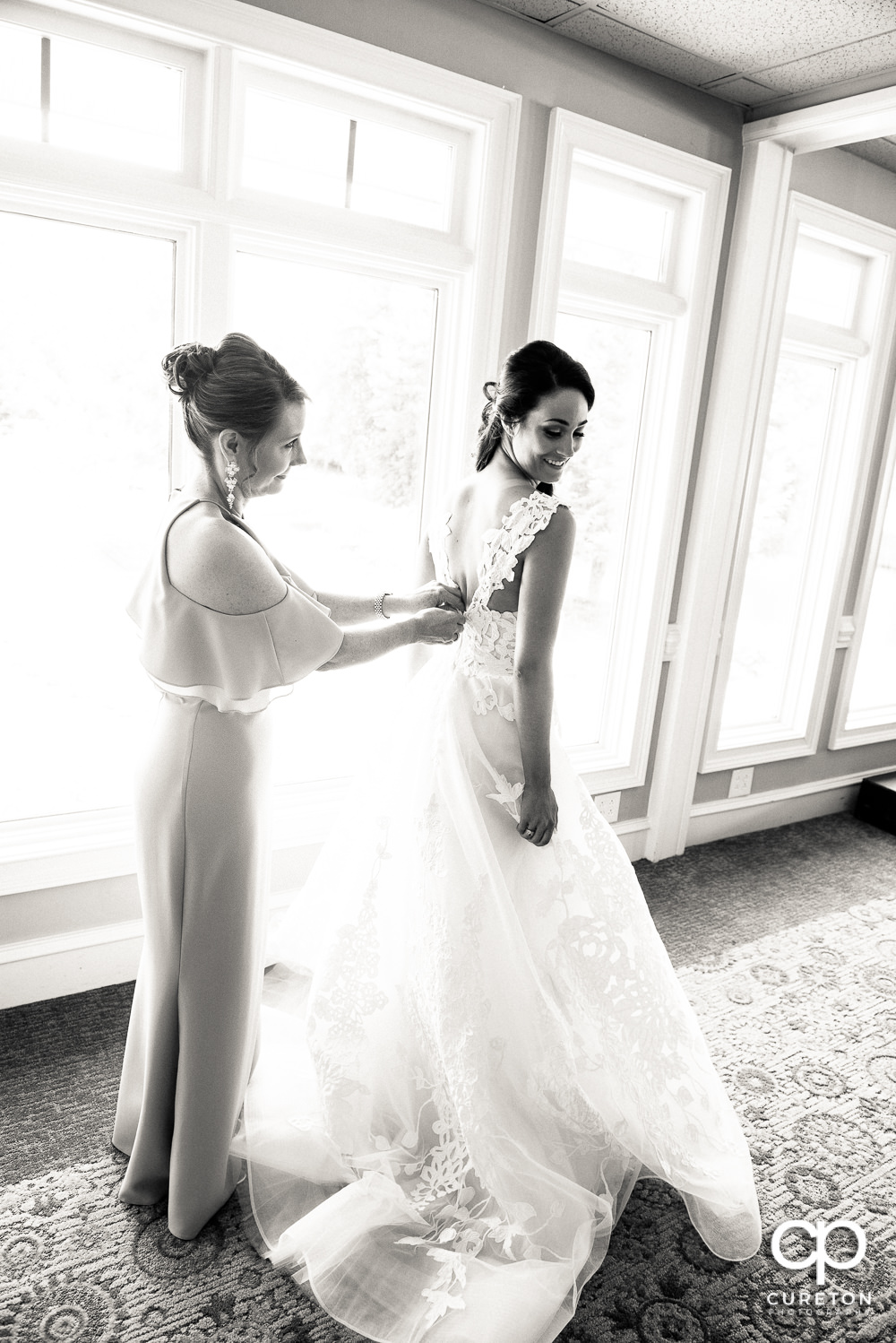 Bride's mom helping her into her wedding dress.