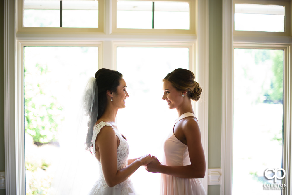 Bride and her sister laughing before the ceremony.