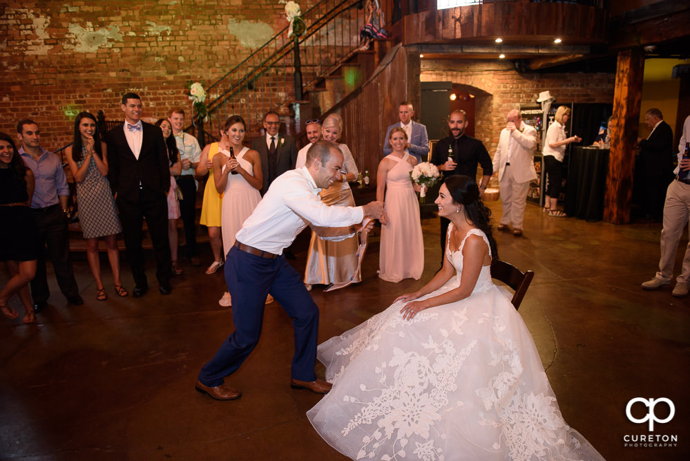 Groom taking off the garter.