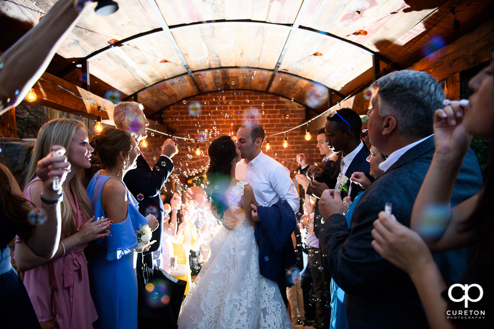 Bride and groom making a grand exit though bubbles at the Old Cigar Warehouse wedding reception.