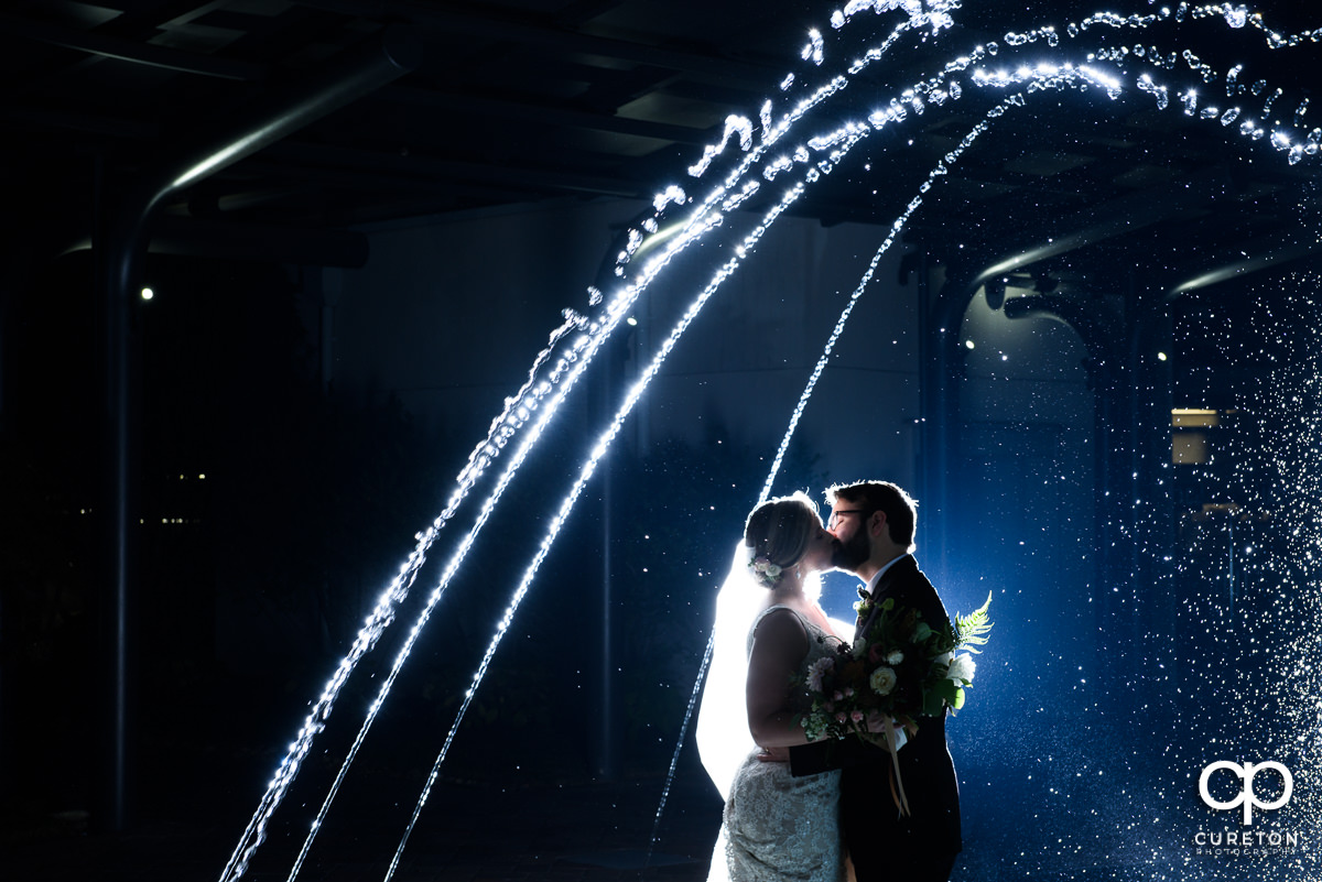 Bride and groom kissing in the fountain at their Greenville Commerce Club wedding.