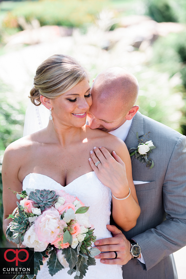 Groom kissing his bride on the shoulder.