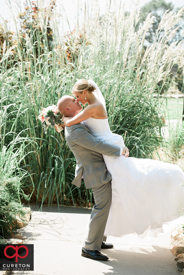 Groom lifting his bride after their wedding.