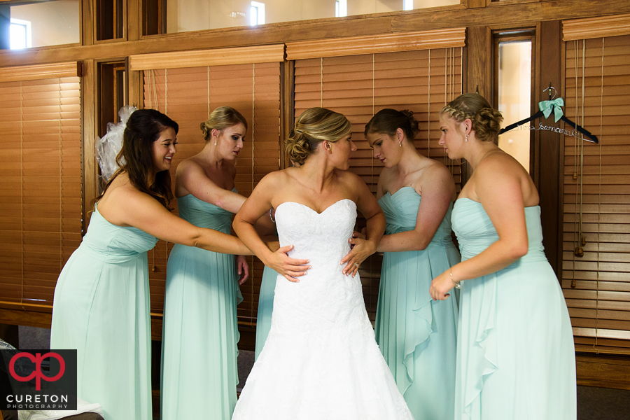Bridesmaids helping the bride into her dress at St. Mary's church.