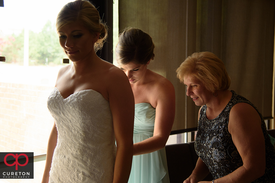 Bride's mom helping her into her dress.