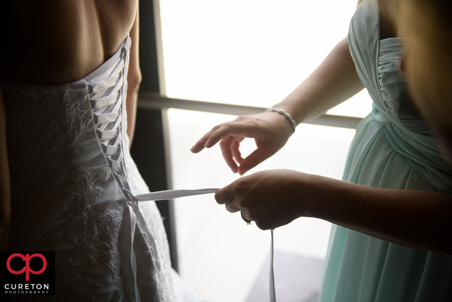 Tying the back of the bride's dress.