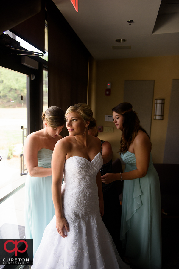 Bridesmaids helping the bride into her dress.