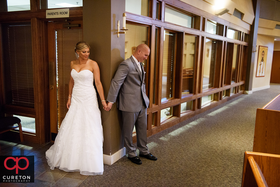 Bride and groom holding hands around a door before the wedding.