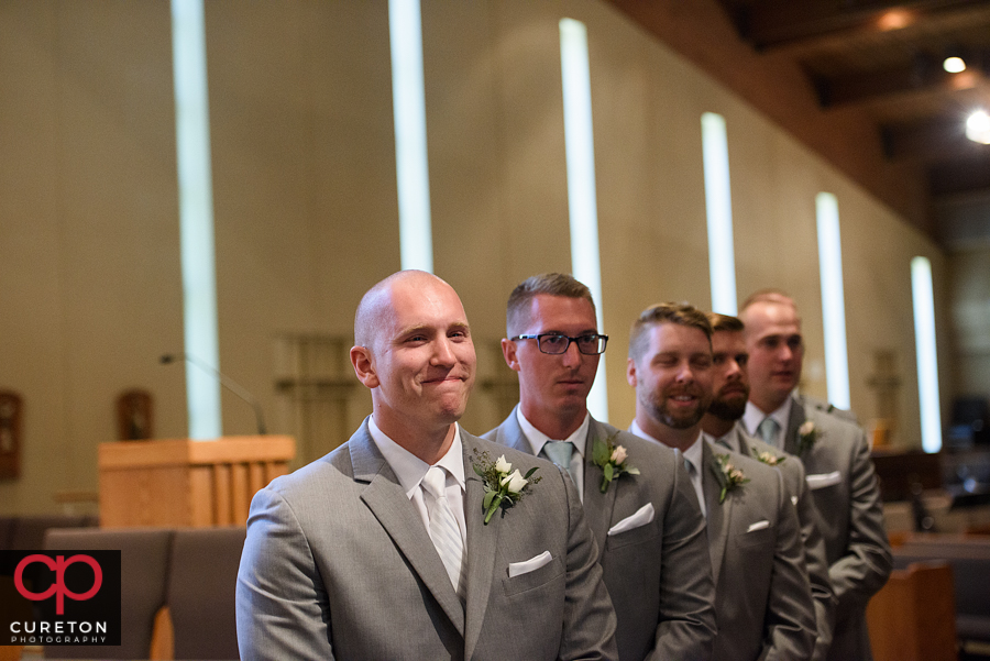 Groom sees his bride for the first time as she walks down the aisle.