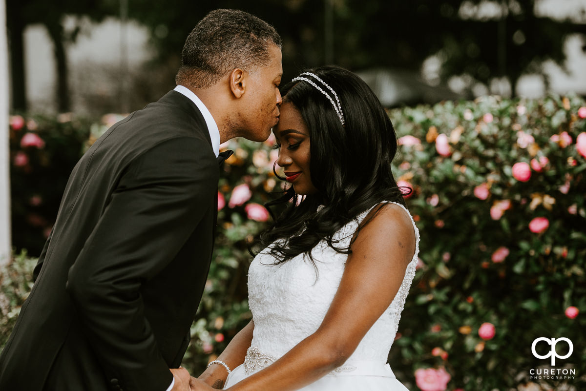 Groom kissing his bride on the forehead in front of the Commerce Club in Greenville,SC.