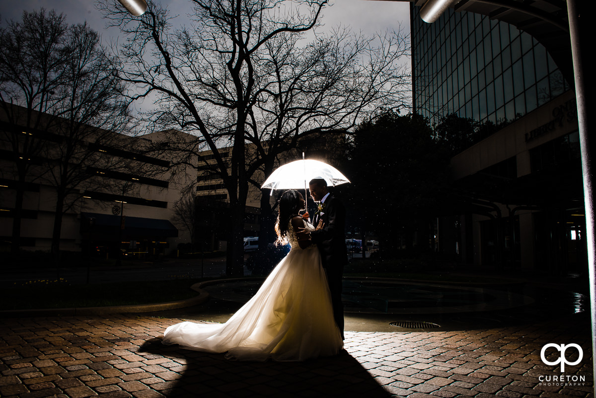 Bride and groom holding an umbrella in the rain at their Commerce Club wedding.