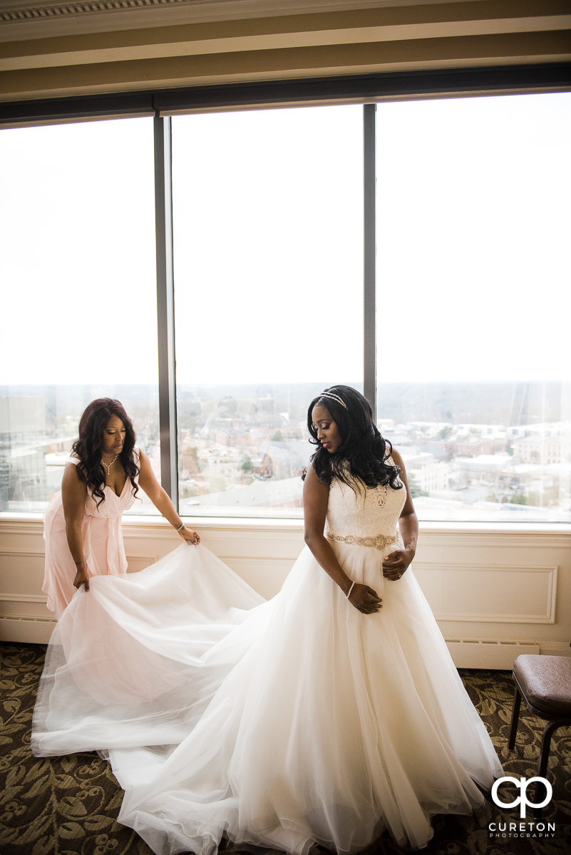 Bride getting helped into her dress by he bridesmaid.