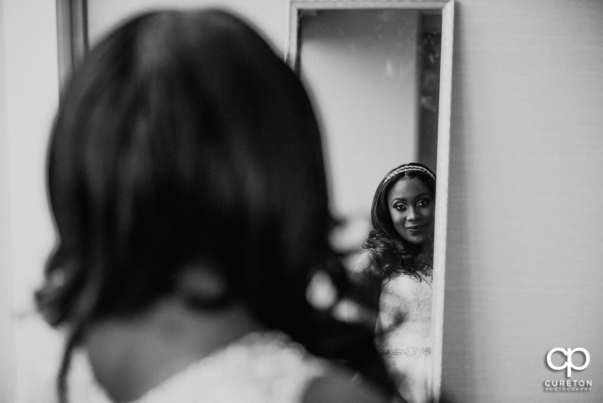 Bride in her dress looking into the mirror.