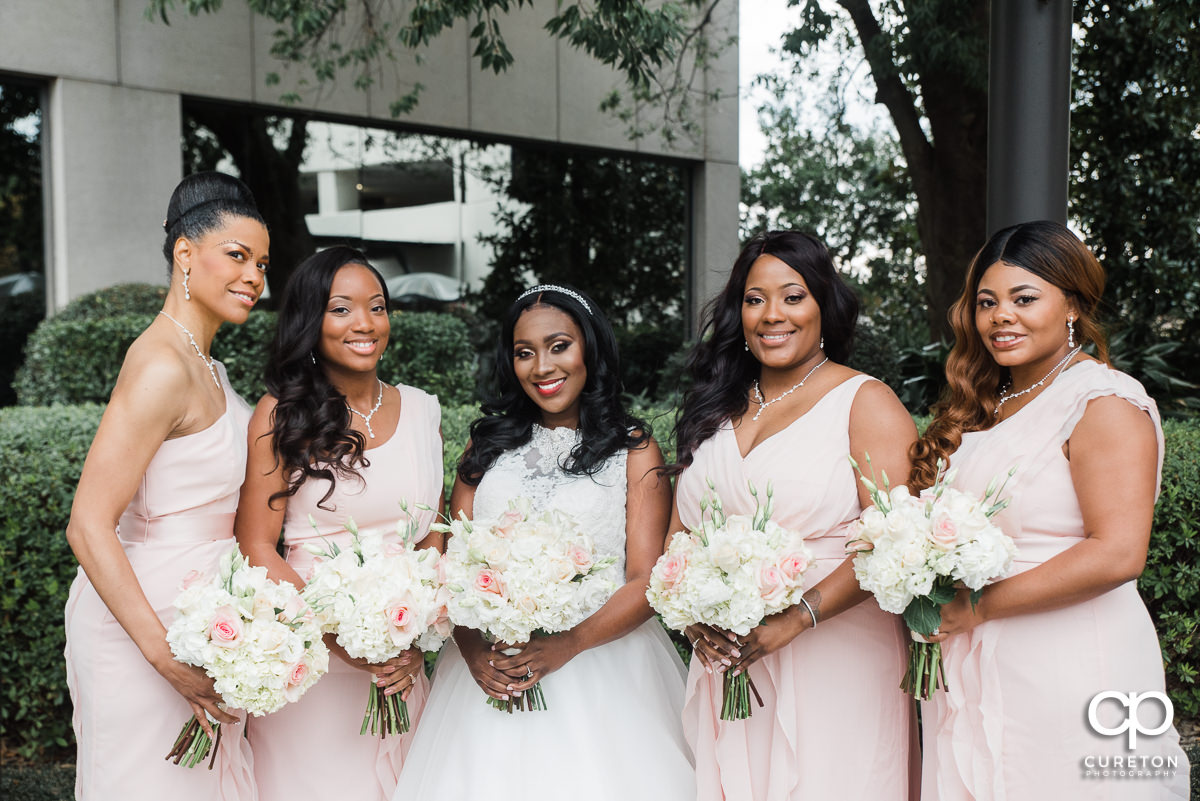 Bride and her bridesmaids holding flowers in front of The Commerce Club.