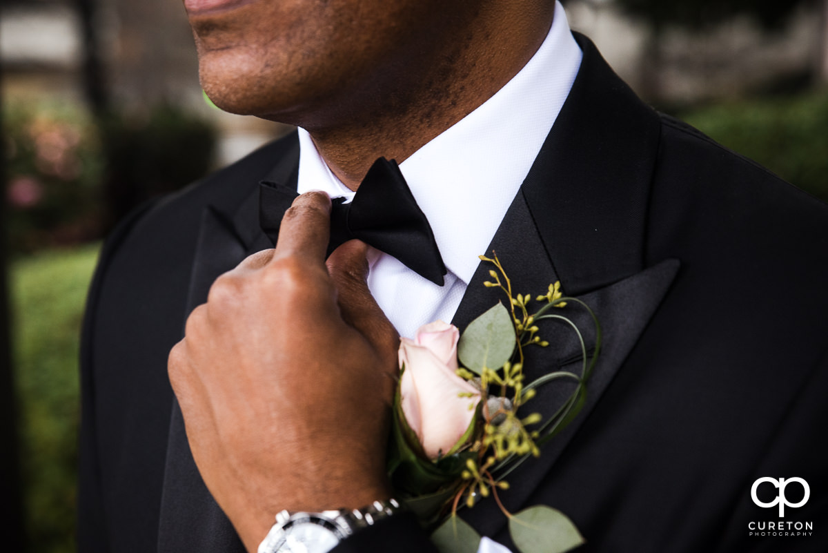 Groom holding his bowtie.