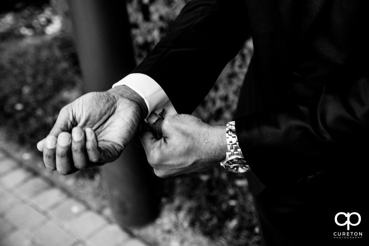 Groom fixing his cufflinks.