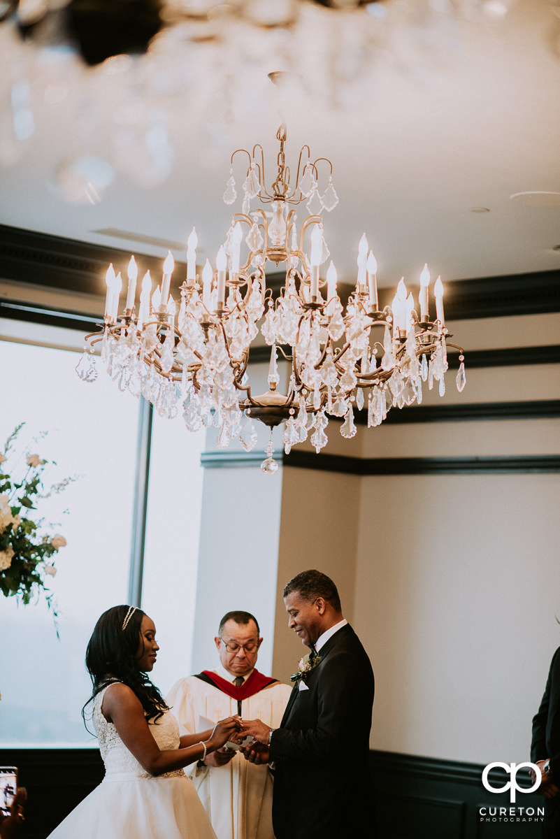 Groom putting the ring on his bride's finger.