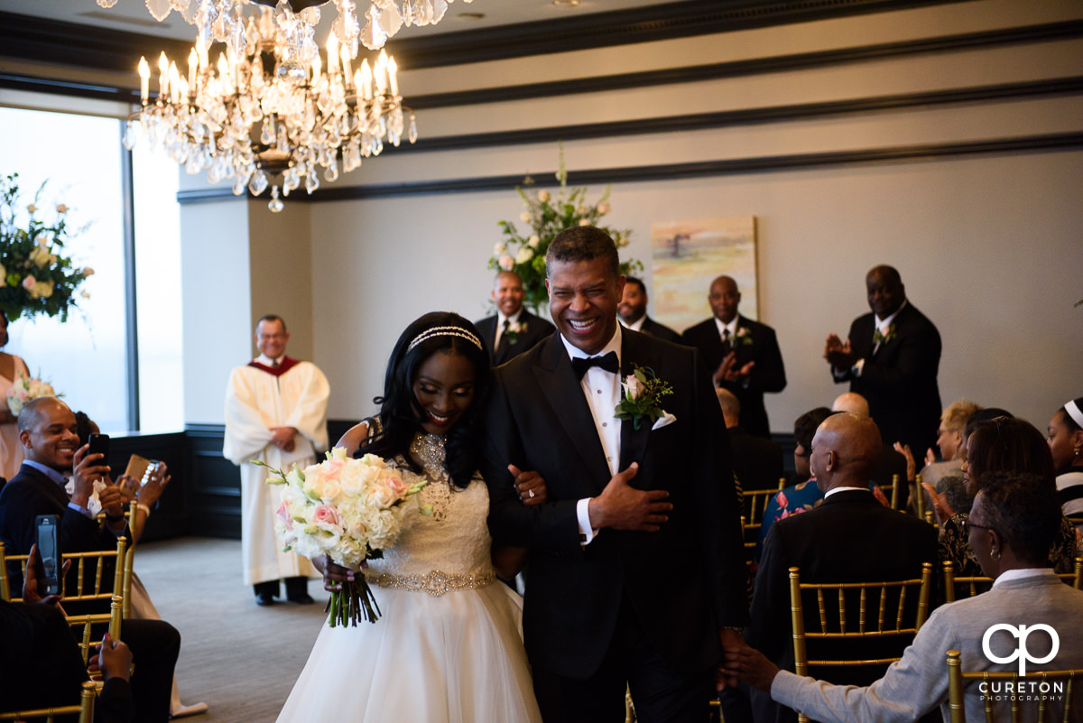 Bride and groom laughing walking back up the aisle at The Commerce Club.