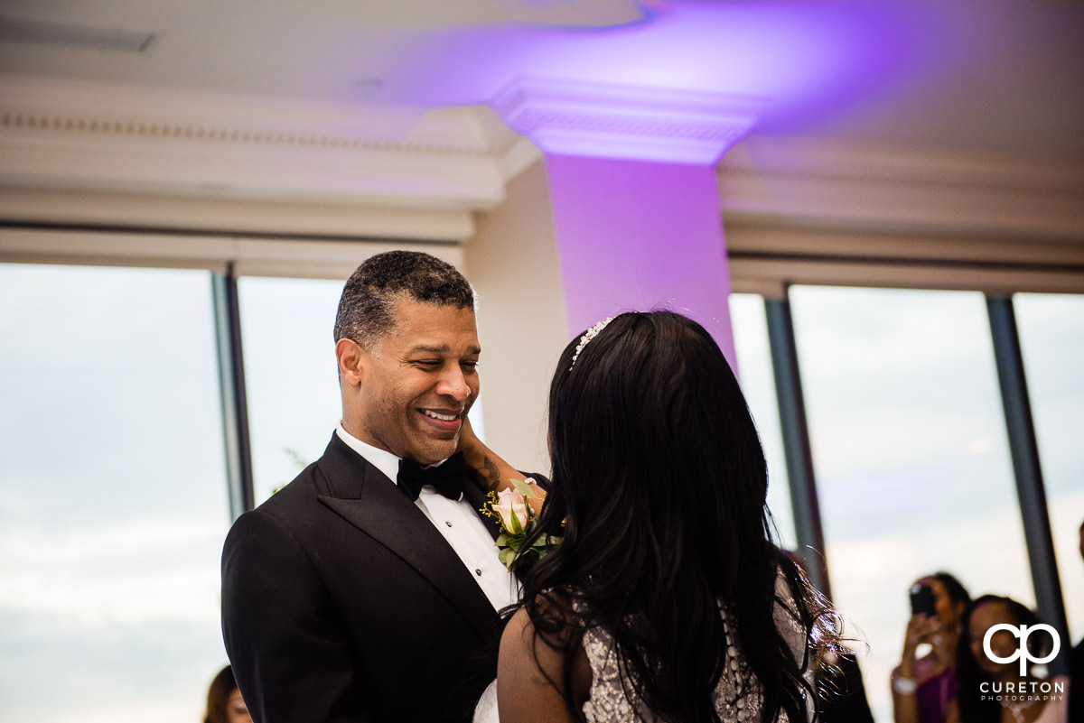 Groom smiling at his bride during their first dance at the wedding reception.