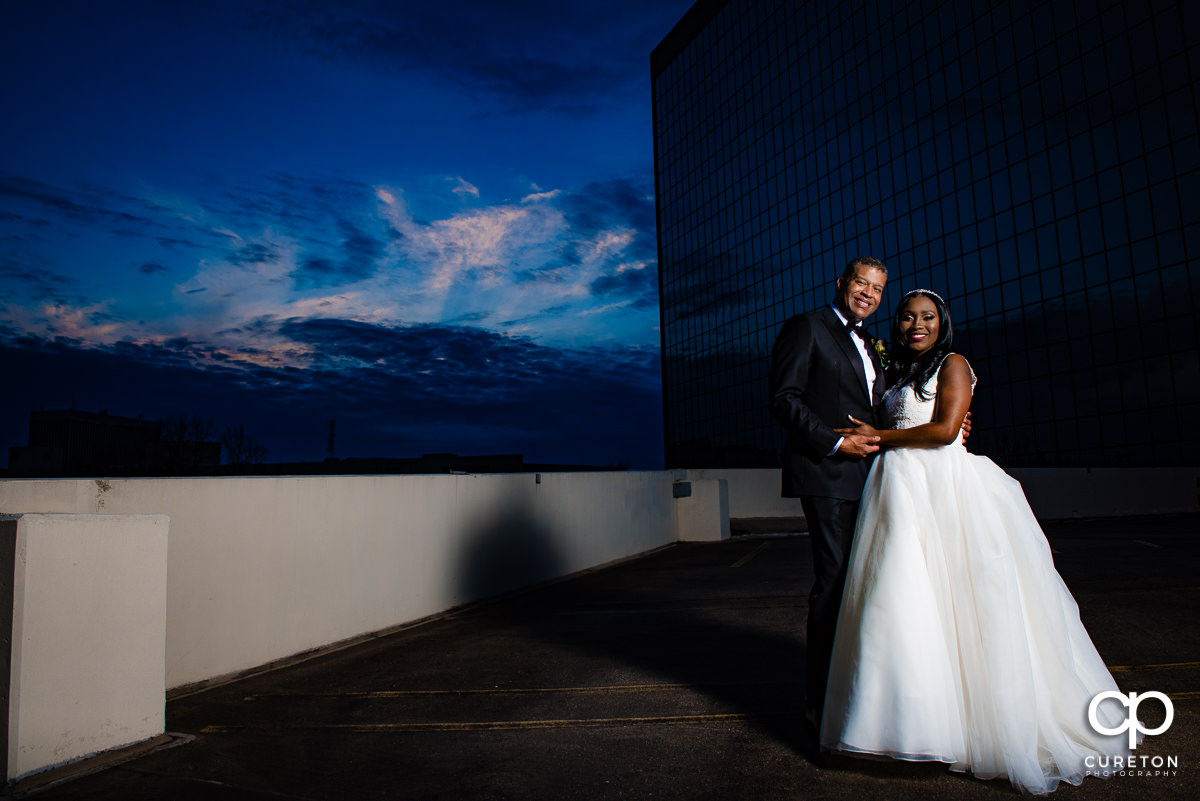 Groom and bride on a rooftop in downtown Greenville at sunset during their wedding reception.