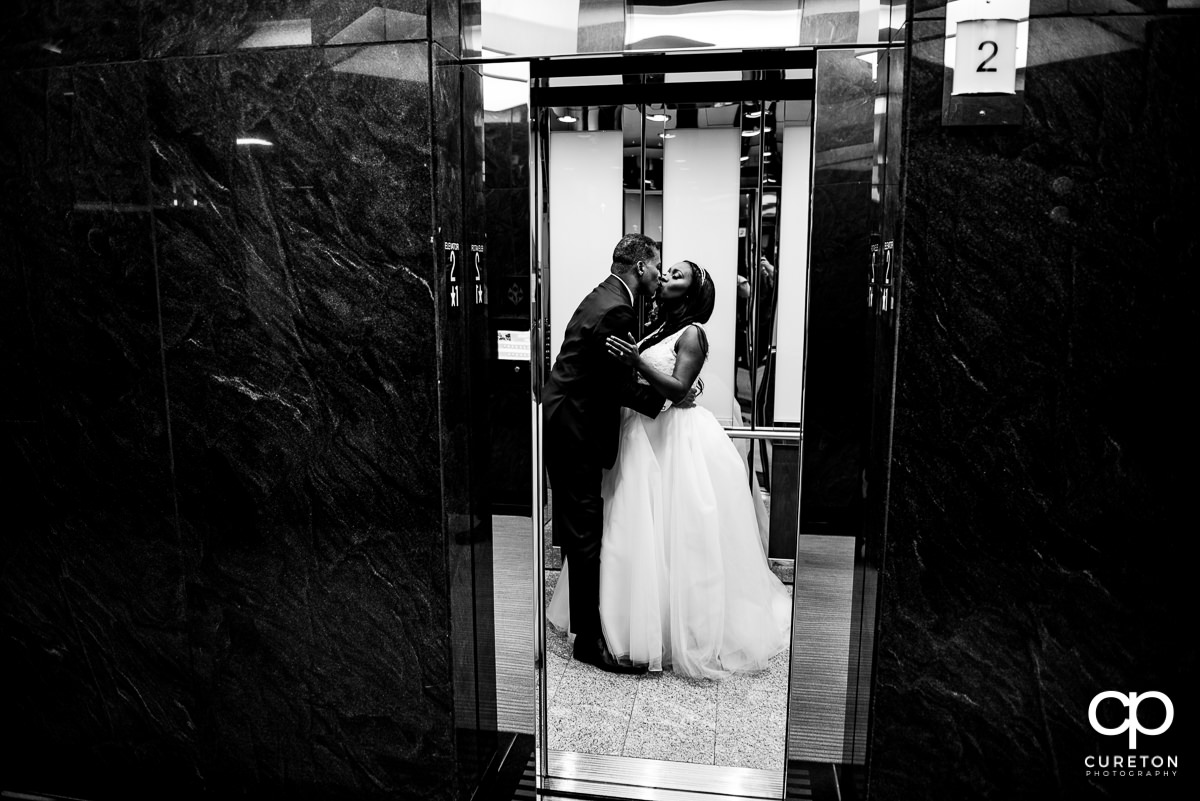 Bride and groom kissing in an elevator.