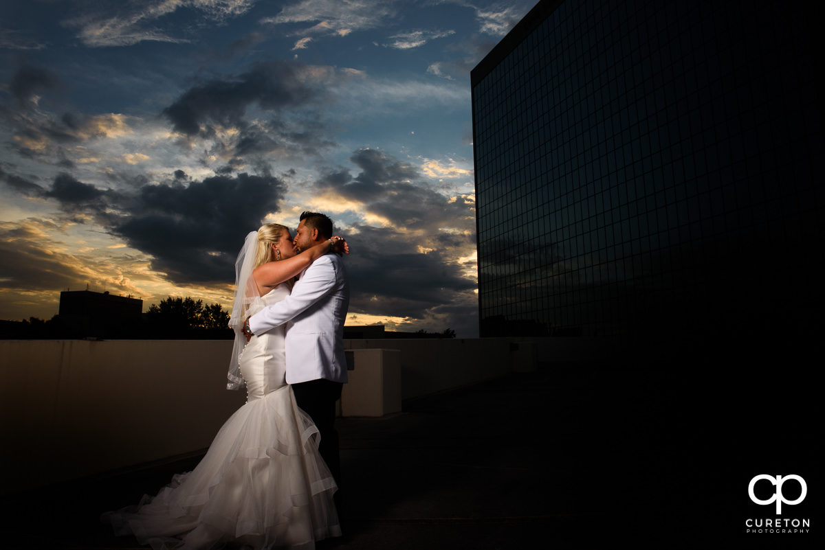 Bride and groom kissing at sunset at their Commerce Club wedding.
