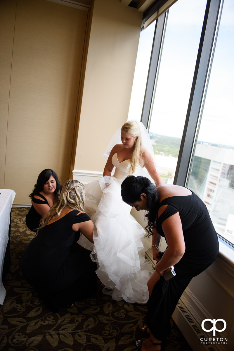 Bridesmaids helping the bride with her garter.