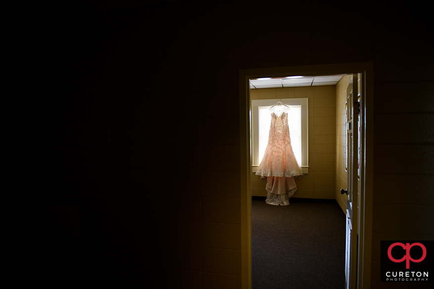 Creative photo of a bride's dress hanging in the window.