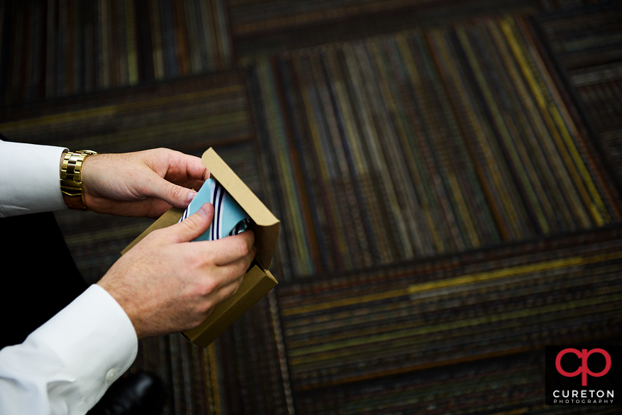 Groom holding a tie that he received as a gift from his bride.