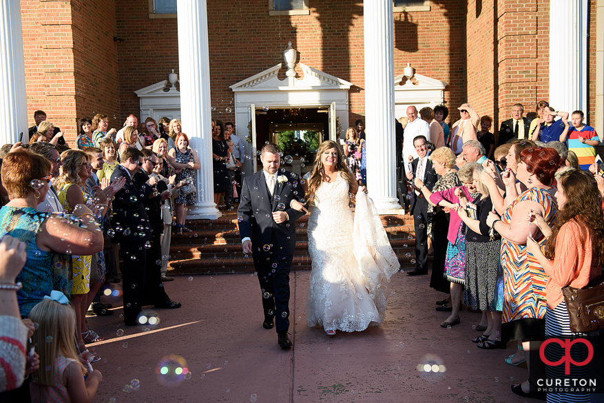 Bride and groom leaving the ceremony through bubbles.