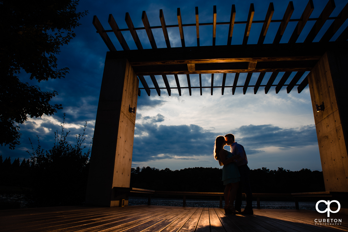 Future Bride and Groom kissing at sunset by the lake during a creative engagement session at Furman University in Greenville,SC