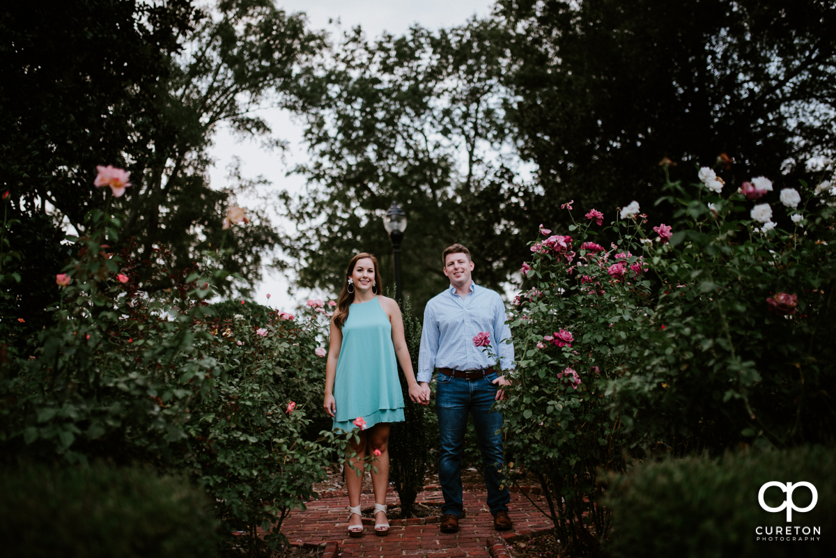 Couple holding hands in the rose garden during a creative engagement session at Furman University in Greenville,SC.