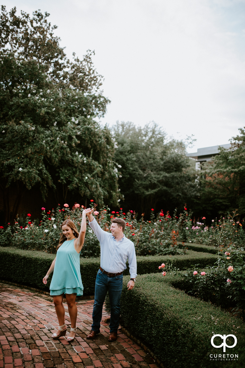 Man spinning his fiancee in the rose garden.