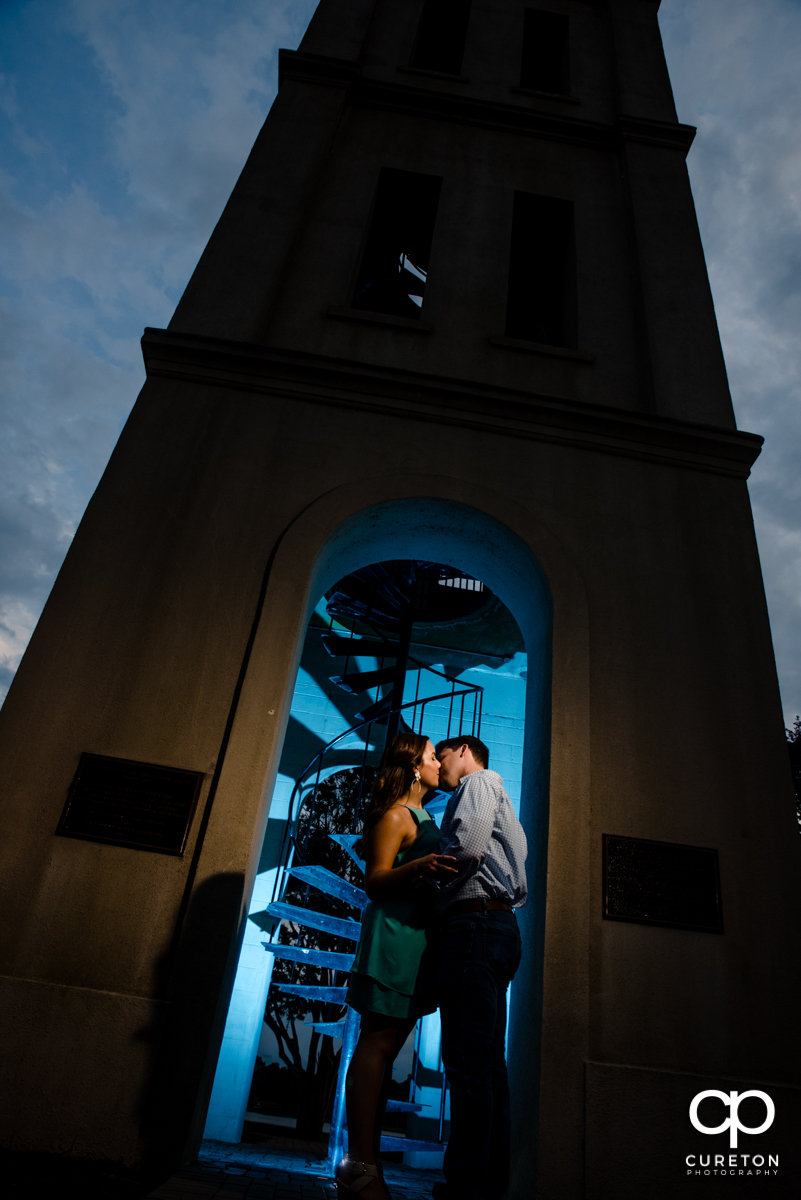 Couple kissing at the Bell Tower by the lake at Furman at their engagement session.