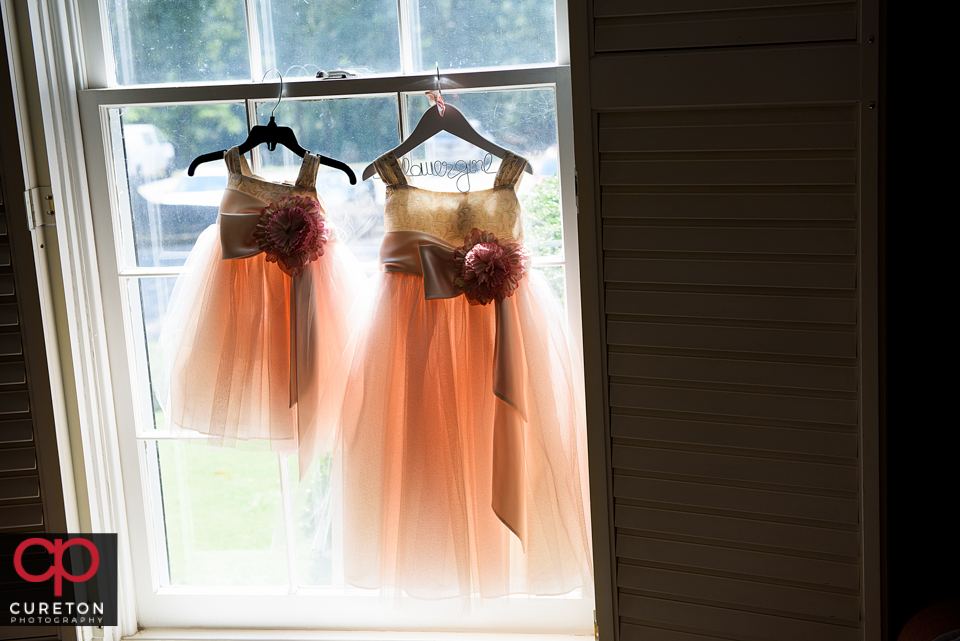 Flower girl dresses hanging in the window.