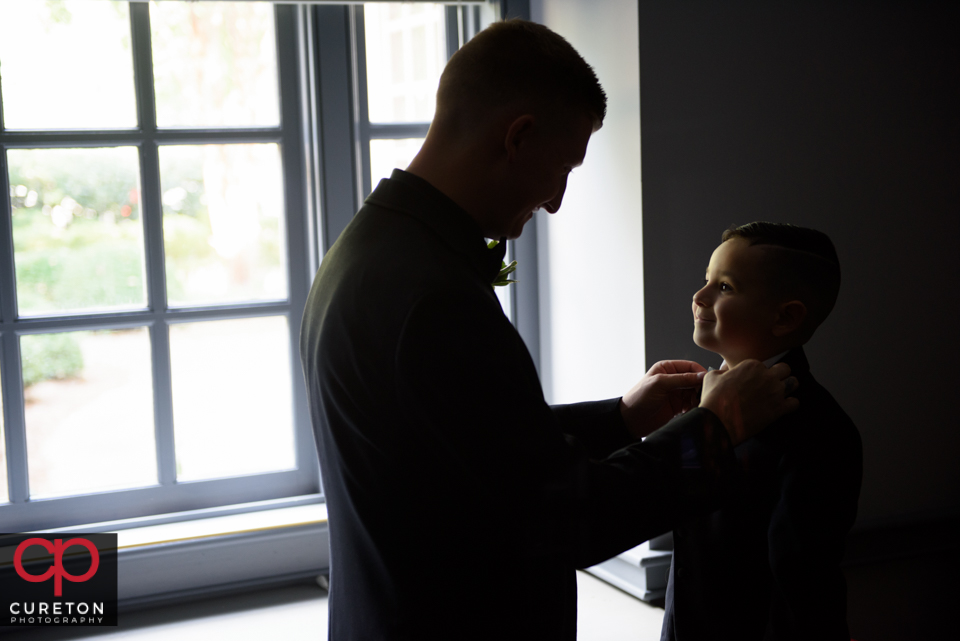 The groom fixing the ringbearers tie.