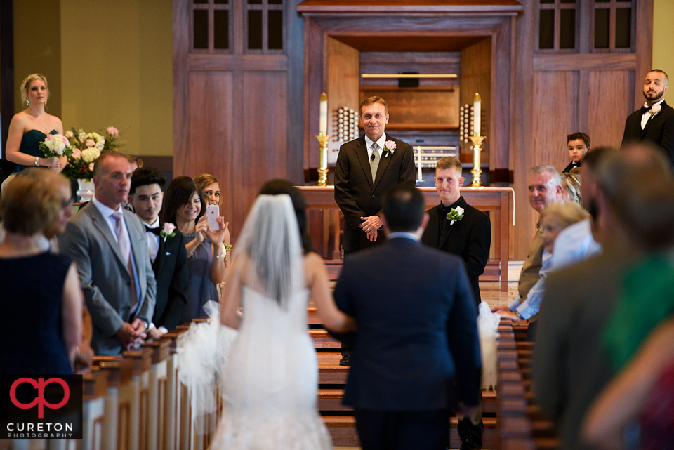 The groom sees his bride for the first time as she walks down the aisle.