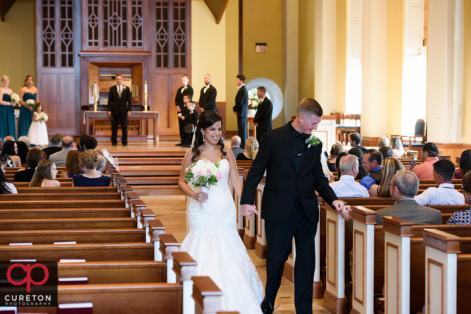 The bride and groom walking back down the aisle after the wedding.