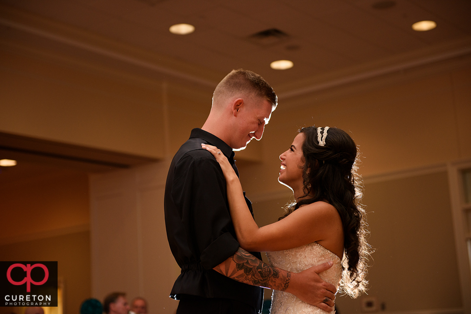 Bride and groom smiling at each other while dancing.