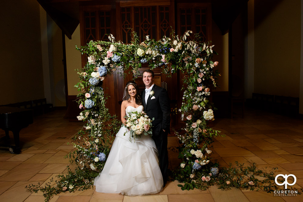 Newlyweds standing in the middle of a gorgeous flower arch.